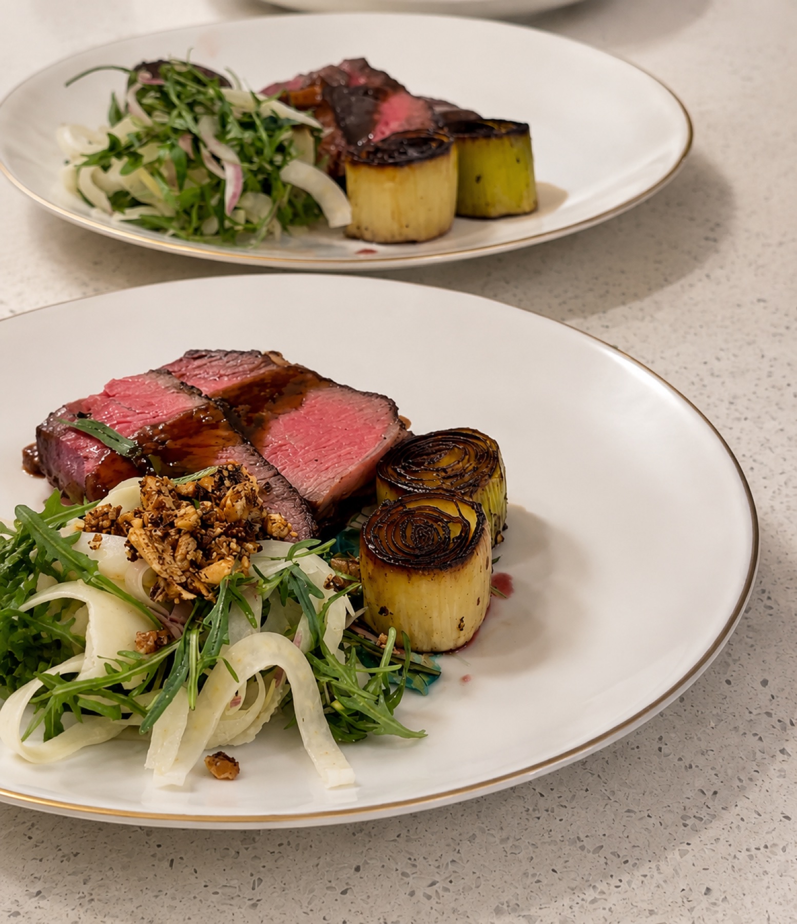 Sliced steak with charred leeks, fennel and arugula salad, spiced granola