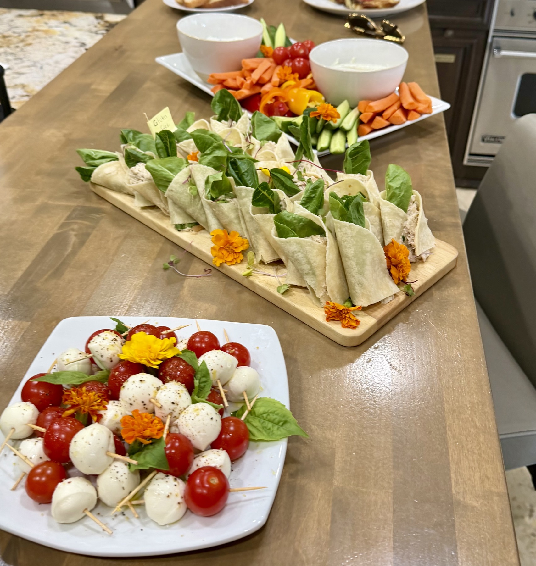 Event spread with caprese skewers, chicken wraps and crudité platter