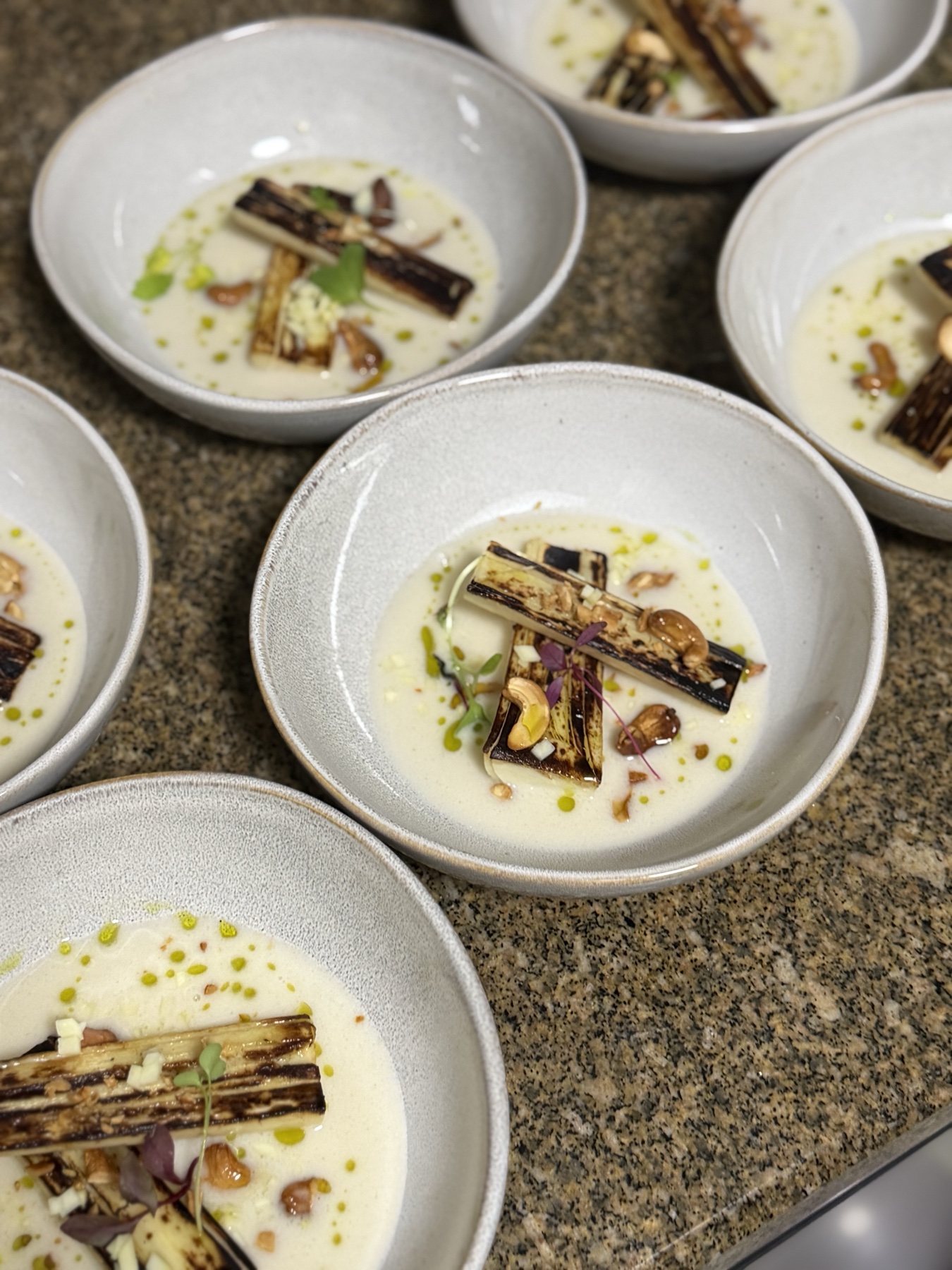 Charred leek in cream soup with cashews and herb oil